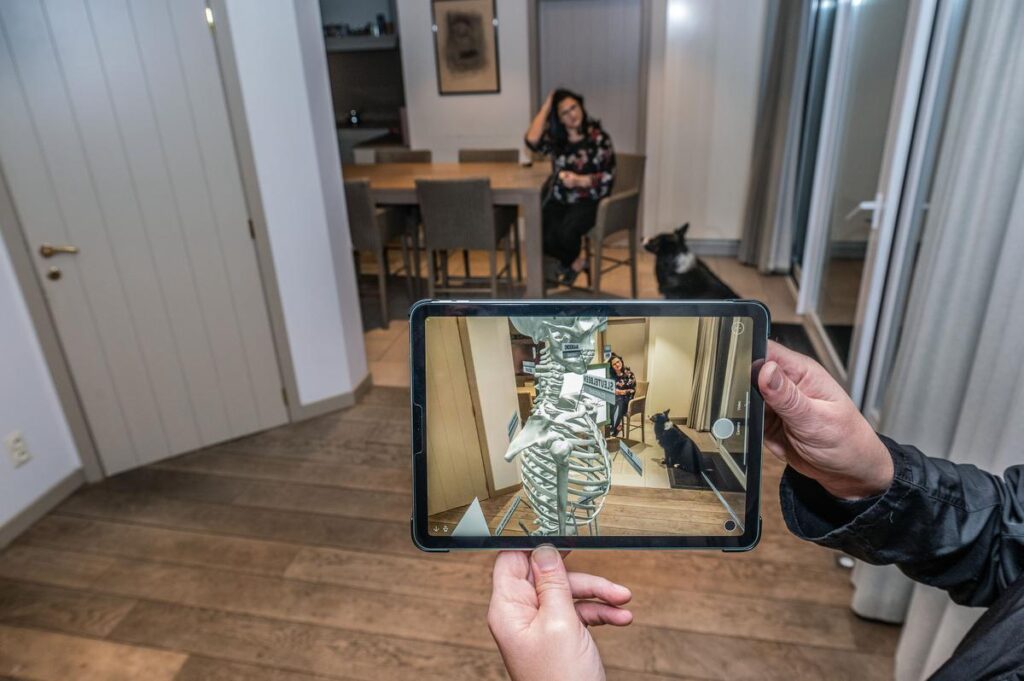 Person holding iPad in center frame viewing skelet model in Augmented Reality